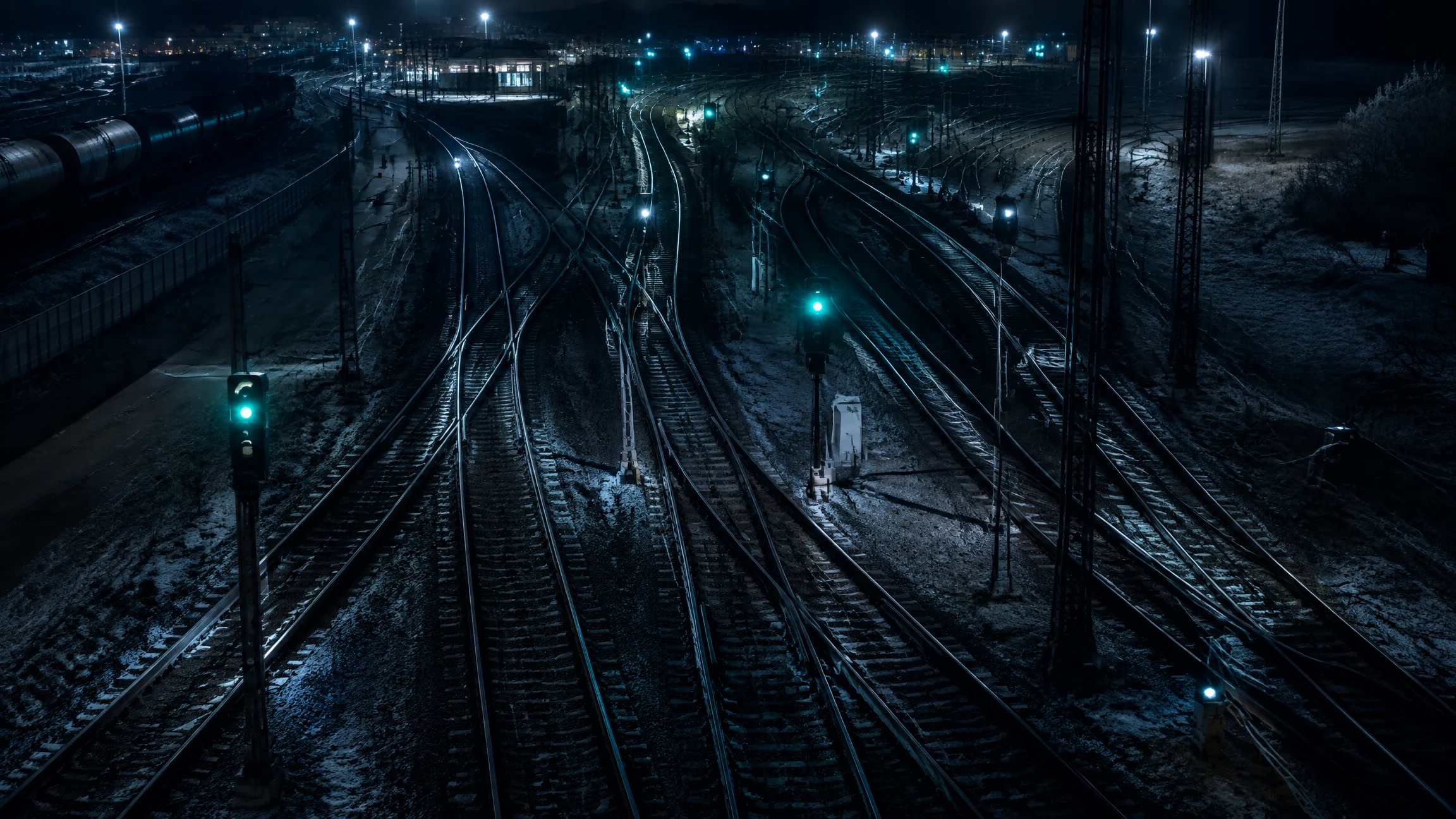 Railway yard at night seen from above with mint and white signal lamps